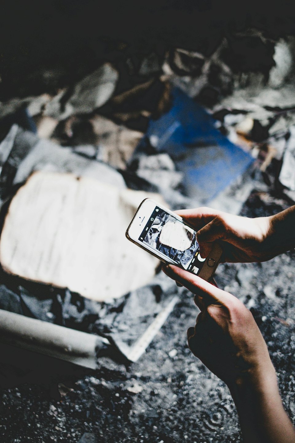 Mani che tengono uno smartphone e scattano una foto di detriti.