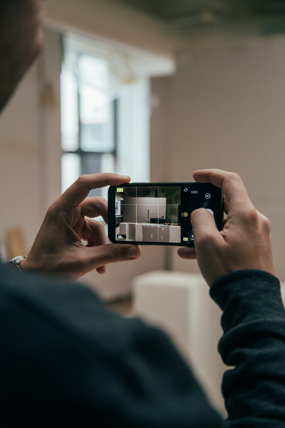 Persona fotografa cantiere con smartphone.