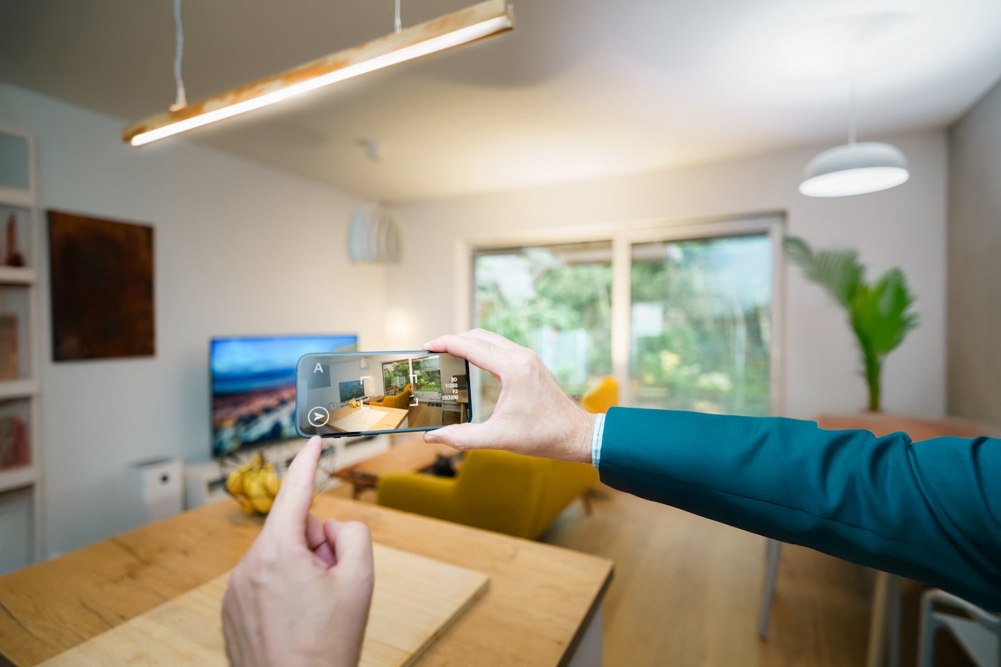 Mani che tengono un telefono che mostra un'app di interior design in realtà aumentata.